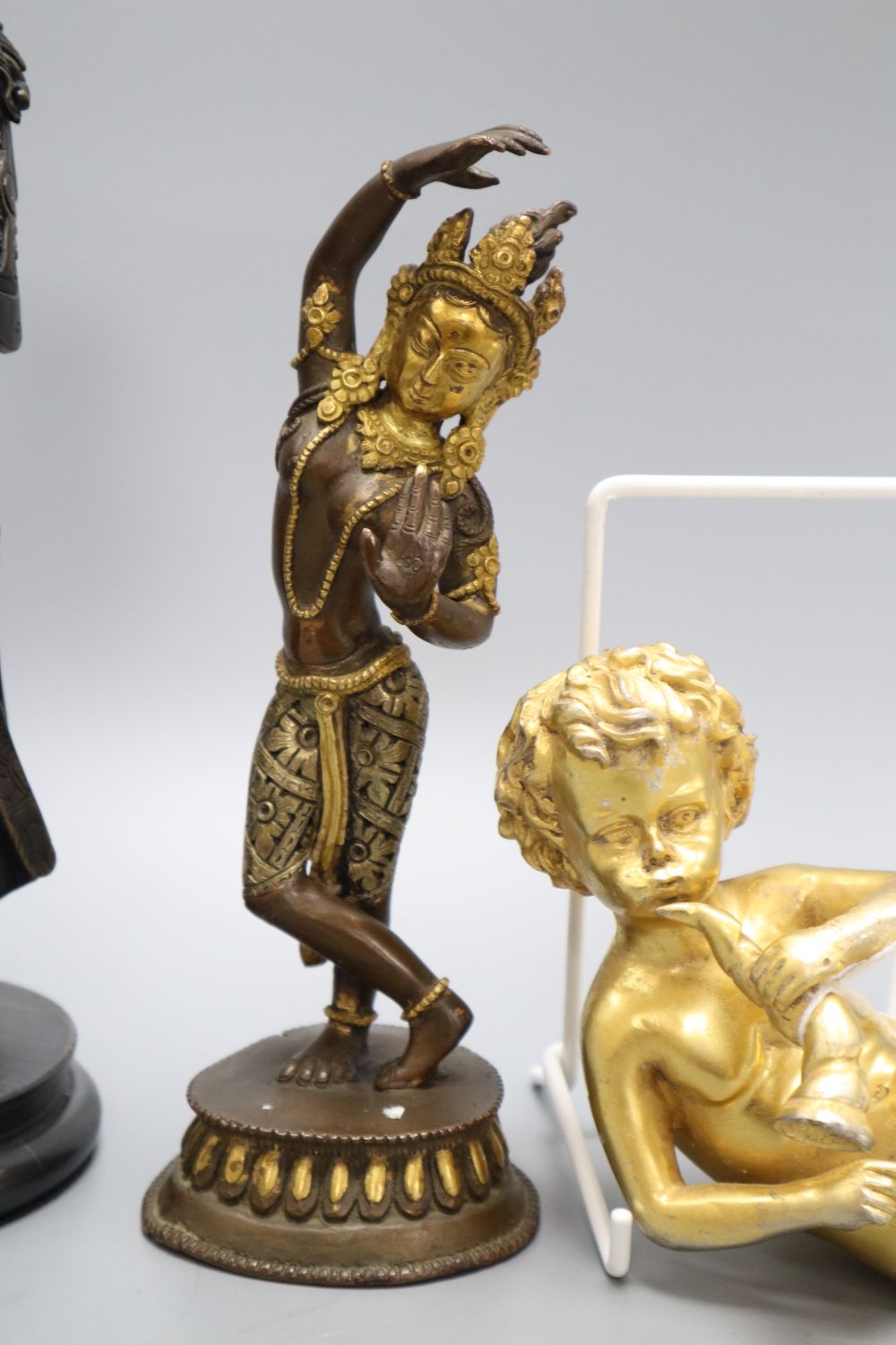 A gilt metal putti playing a musical conch shell, an Indian deity and a sage, tallest 26cm